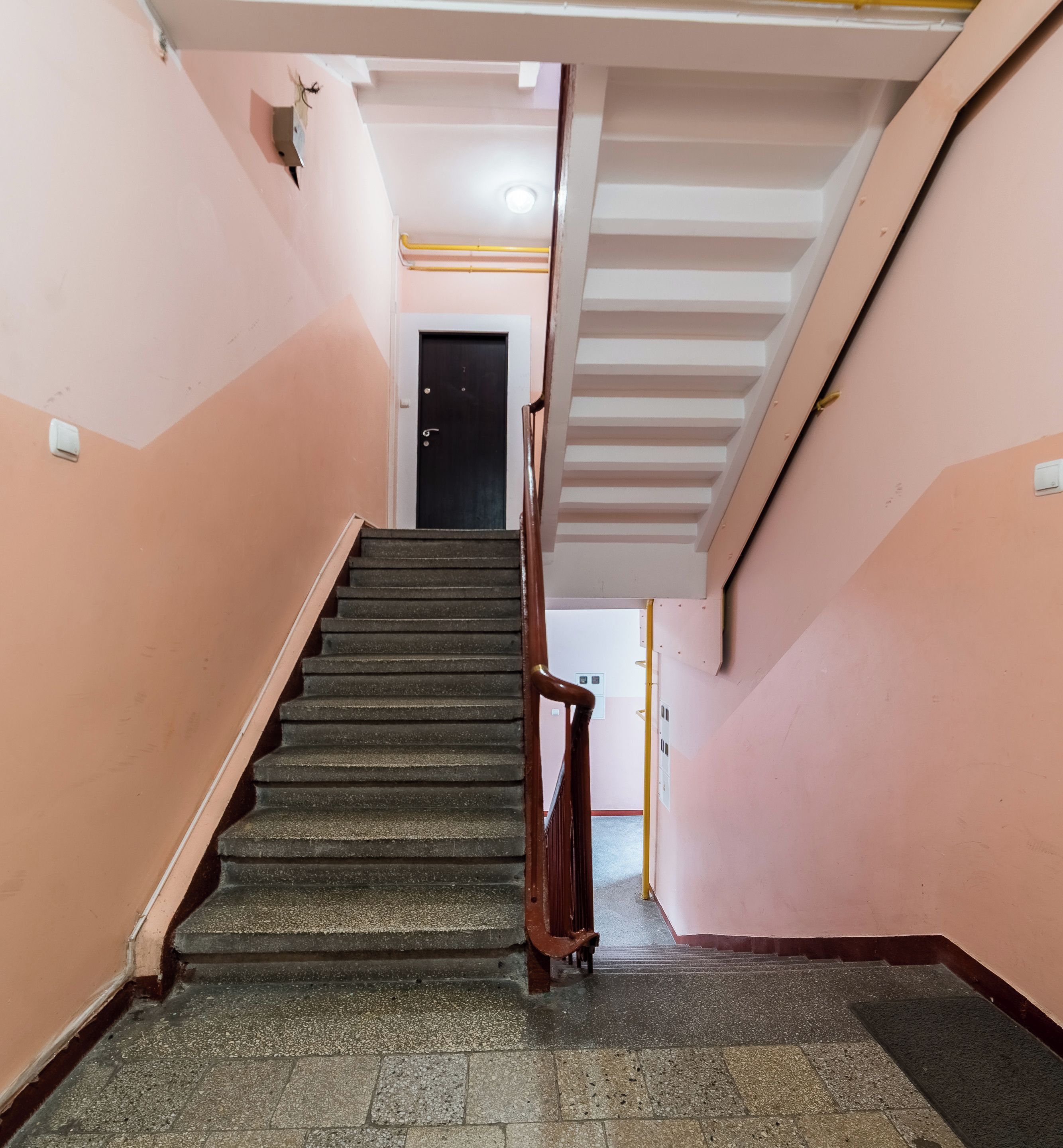 A staircase with a handrail leading to a door at the top.