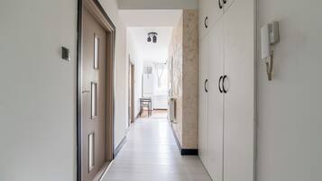 A corridor with a door on the left, a chair in the middle, and cabinets on the right.