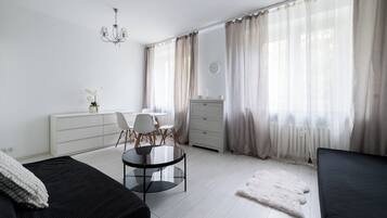Ein modernes Schlafzimmer mit Bett, Schreibtisch, Stuhl, Kommode und einem großen Fenster mit Vorhängen.