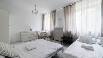 Ein modernes Schlafzimmer mit zwei Betten, einem Schreibtisch, einem Stuhl, einer Kommode und einer Wanduhr.