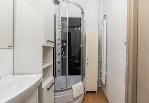 Ein Badezimmer mit einer Duschkabine aus Glas, einem weißen Waschbecken und einem Schrank.