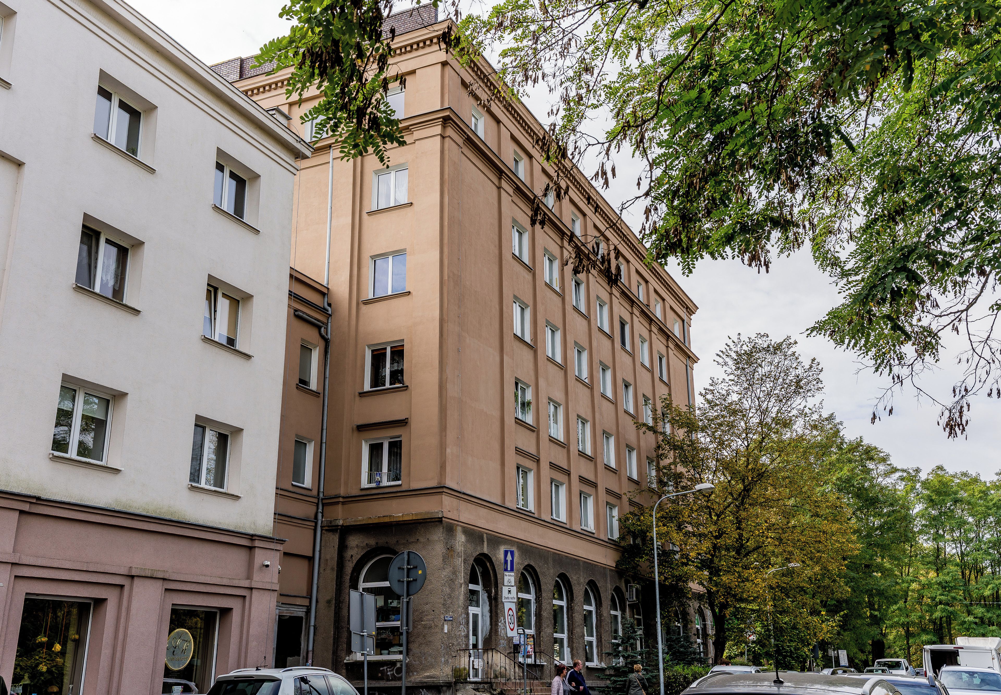 A multi-story building with a mix of architectural styles, including a corner building with arched windows and a flat-roofed building with rectangular windows.