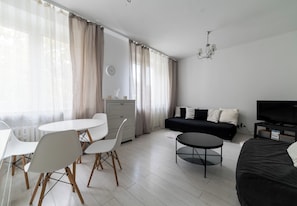 Ein modernes Wohnzimmer mit Essbereich, einer Couch, einem Fernseher und einer Pendelleuchte.