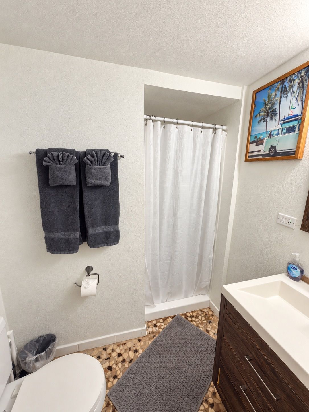 Un baño con inodoro, lavamanos, cortina de ducha y toallas.