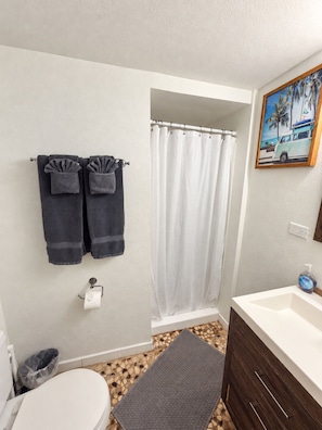Une salle de bain équipée de toilettes, d’un lavabo, d’un rideau de douche et de serviettes.