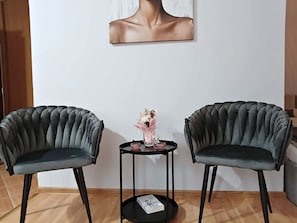 Dos sillones tapizados con asiento y respaldo acolchados, ubicados a cada lado de una pequeña mesa redonda con base negra.