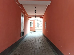 Un pasillo con piso de baldosas, techo blanco y una lámpara colgante.