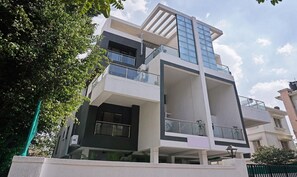 Um edifício de vários andares com design arquitetônico moderno, apresentando varandas com guarda-corpos de vidro e um telhado plano.