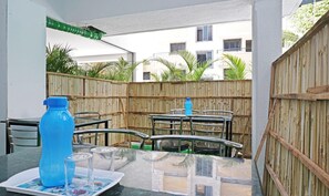 Área de varanda externa com mesa, cadeiras e uma garrafa de água azul.