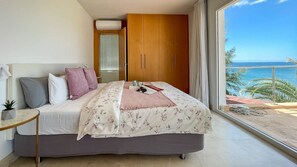 A bedroom with a bed, a bedside table, a wardrobe, and a view of the sea. - Nueva Suecia 716 Studio (San Agustin)