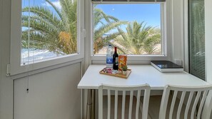 Et værelse med et hvidt bord ved et vindue, hvor palmerne kan ses.