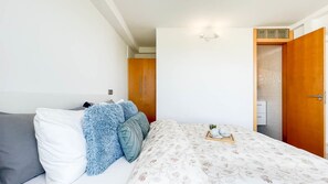 A bedroom with a bed, a nightstand, a wooden wardrobe, and a bathroom visible through an open door. - Nueva Suecia 716 Studio (San Agustin)