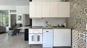 Eine kompakte Küche mit Backofen, Geschirrspüler und einer kleinen Arbeitsfläche mit Spüle.