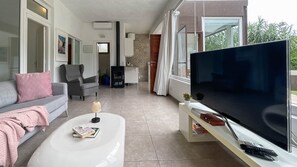 A modern living room with a sofa, a coffee table, a flat-screen TV, and a small table with a plant. - Villa Barranco de los Cernícalos - 2-Bedroom Cabin (Vegas, Las (Valsequillo))