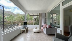 Un salon moderne avec un canapé, un pouf et un téléviseur à écran plat.