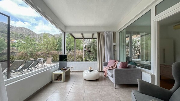 Un salon moderne avec un canapé, un pouf et un téléviseur à écran plat.