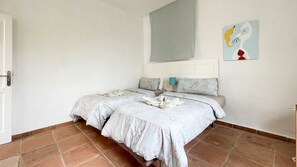 Ein Schlafzimmer mit einem Bett, einem Nachttisch, einer Wandleuchte und einem Gemälde.