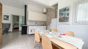 A modern kitchen with white cabinets, a built-in oven, and a dining area with a table set for two. - Villa Barranco de los Cernícalos - 2-Bedroom Cabin (Vegas, Las (Valsequillo))