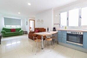A modern kitchen with a built-in oven and a dining area with a table and chairs. - Sagasta Canteras Apartment (Palmas De Gran Canaria, Las)