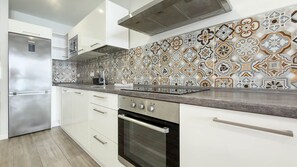 A modern kitchen with a stainless steel refrigerator, white cabinetry, and a patterned backsplash. - Guanarteme Vista Surf, Las Canteras 2 (Palmas De Gran Canaria, Las)