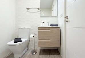 Une salle de bain moderne avec des toilettes, un lavabo et un miroir.