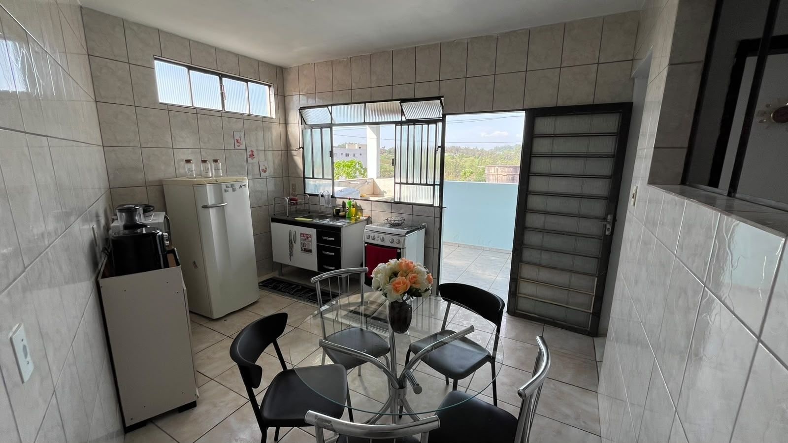 A compact kitchen with a dining area, a refrigerator, a stove, and a window with a view.