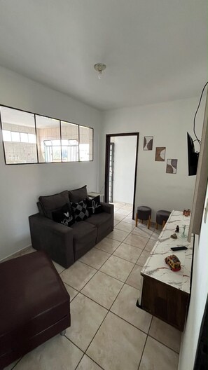 A living room with a sofa, a coffee table, and a dining area with a table and chairs.