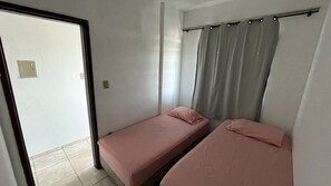Una habitación con dos camas individuales, una puerta corredera y una cortina.