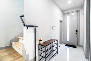 A modern staircase with a wooden finish, a metal handrail, and a small table with a potted plant. - DT Sky Lounge|FirePit+PoolTbl+Golf+Sauna|Sleeps16 (Dallas)