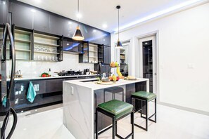 A modern kitchen with a central island, bar stools, and pendant lighting. - DT Sky Lounge|FirePit+PoolTbl+Golf+Sauna|Sleeps16 (Dallas)