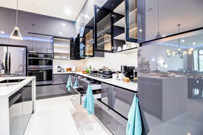 A modern kitchen with a central island, stainless steel appliances, and a view of the living area. - DT Sky Lounge|FirePit+PoolTbl+Golf+Sauna|Sleeps16 (Dallas)