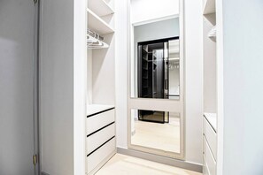 A walk-in closet with open shelves, a mirrored closet door, and a wooden floor. - DT Sky Lounge|FirePit+PoolTbl+Golf+Sauna|Sleeps16 (Dallas)