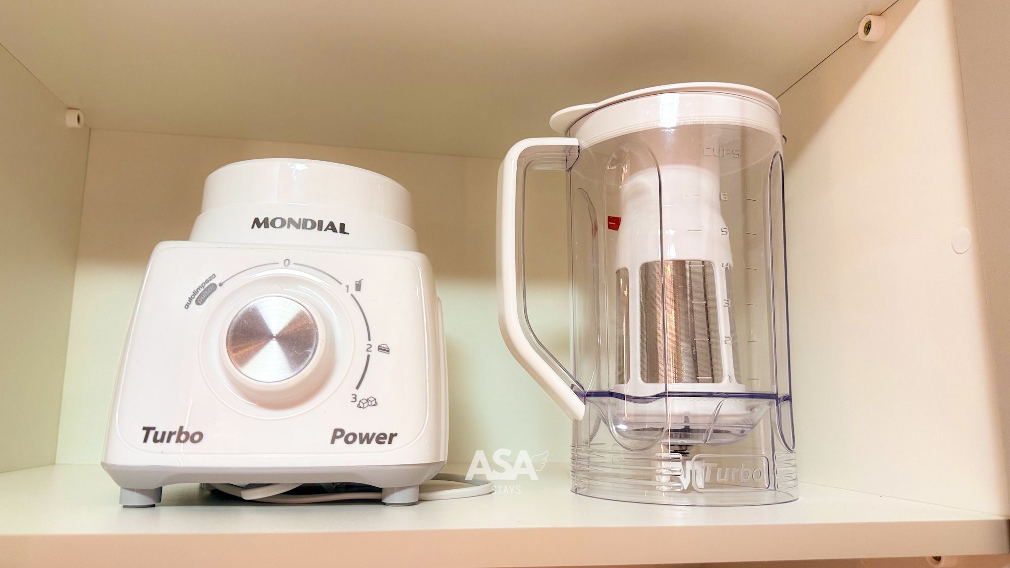 A white Mondial Turbo Power blender and a clear glass pitcher on a shelf.