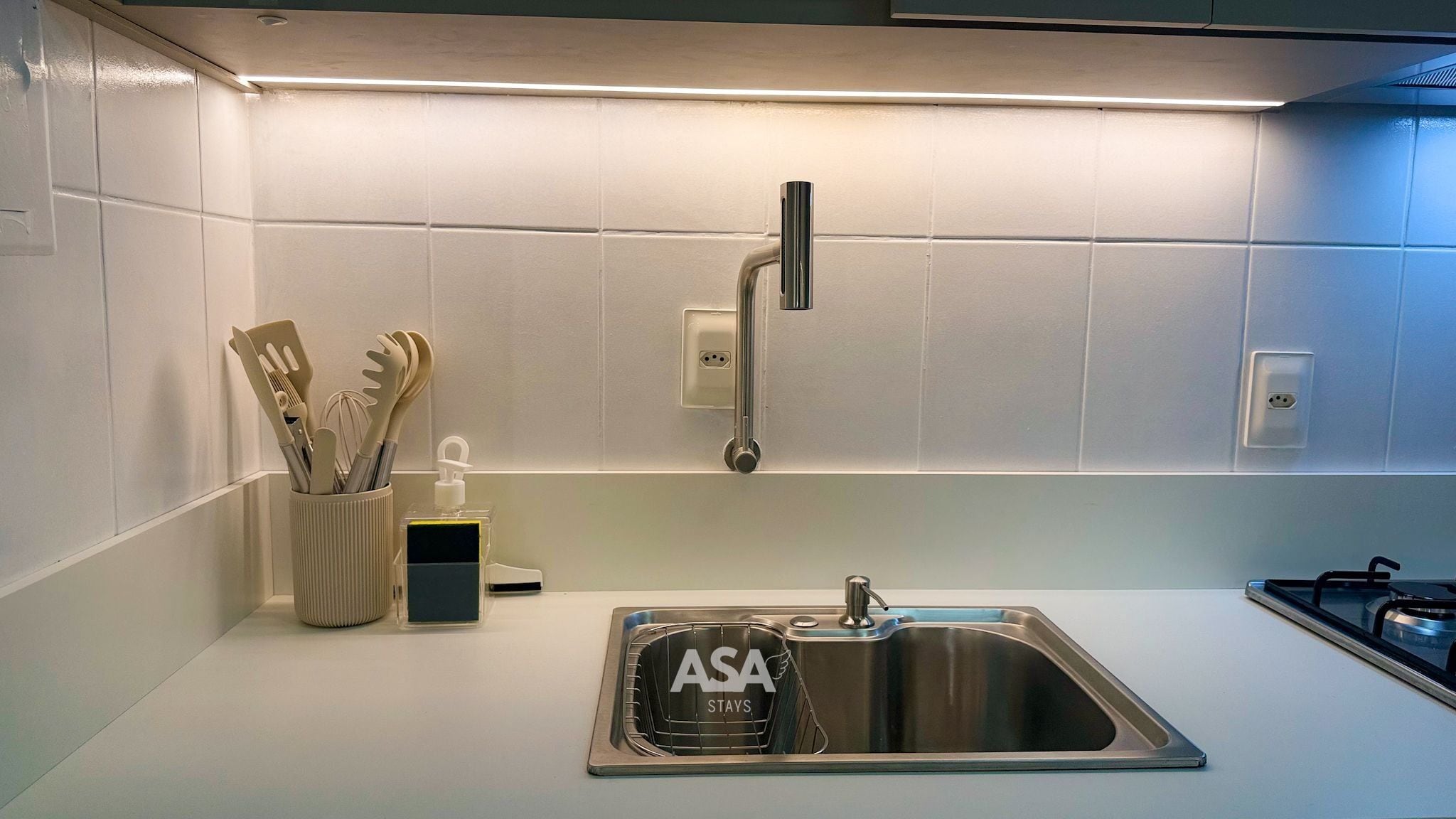 A modern kitchen with a stainless steel sink, a faucet, and a range hood.