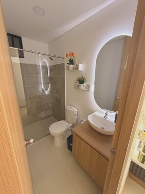 A modern bathroom with a glass-enclosed shower, a toilet, a sink, and a mirror. - New Listing (Montenegro)