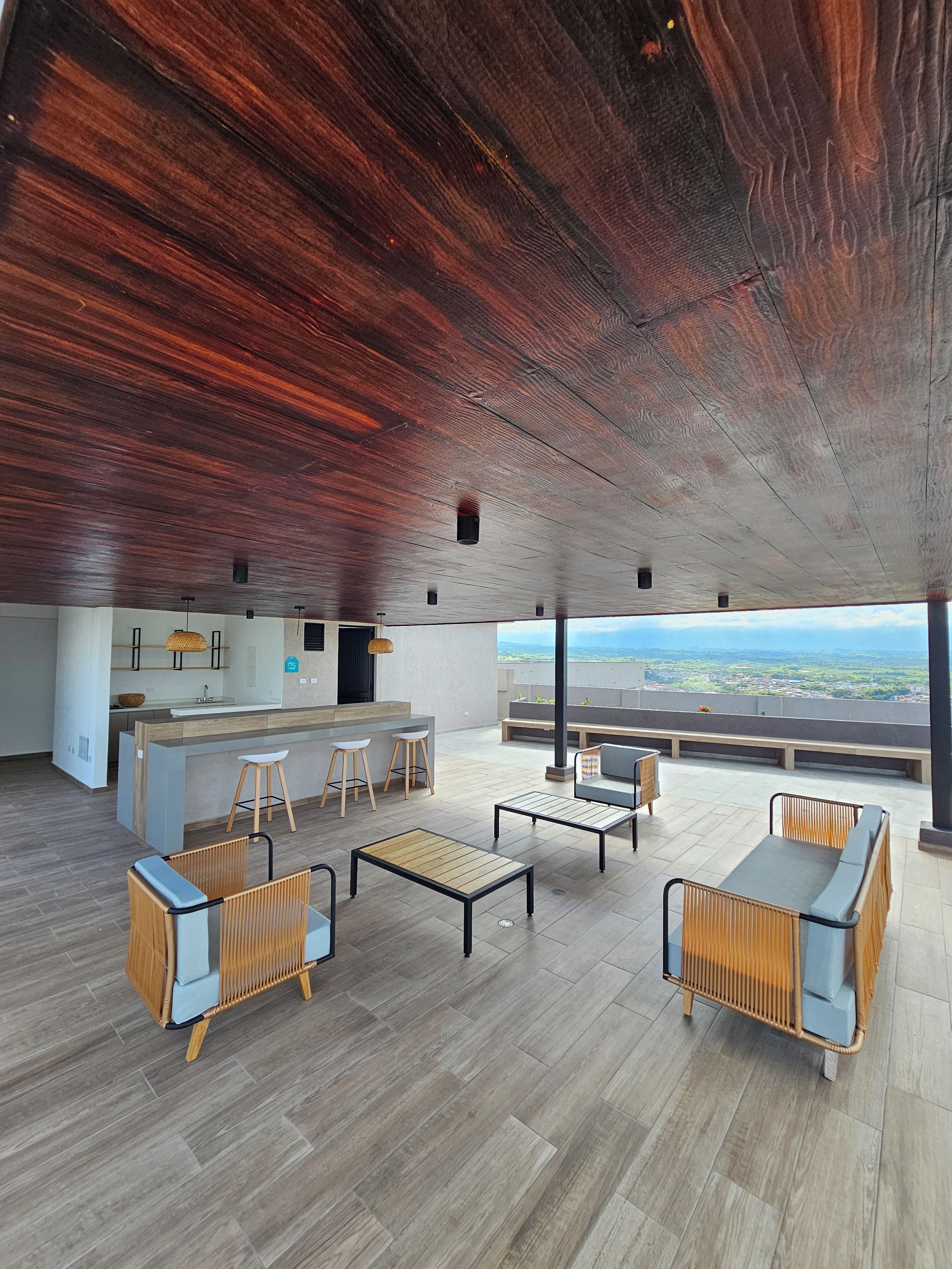 A spacious living area with a high ceiling, a kitchen area, and a view of the landscape.