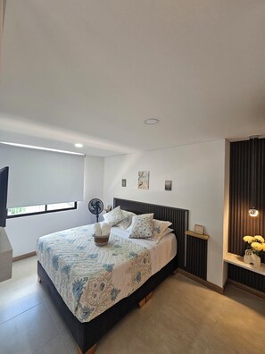 A modern bedroom with a large bed, a standing fan, and a window with blinds. - New Listing (Montenegro)