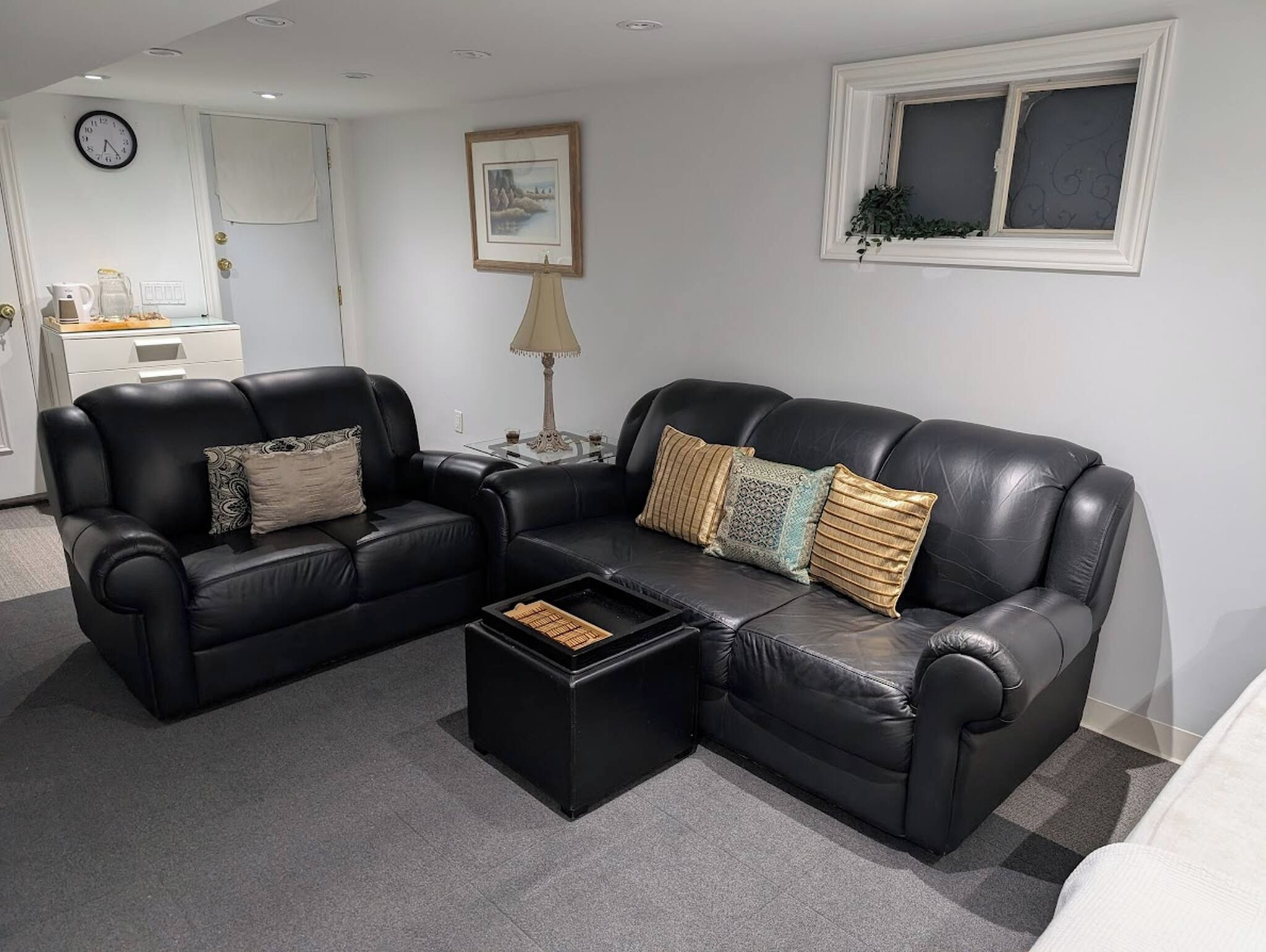 A living room with a black leather sofa, a coffee table, and a side table with a lamp.
