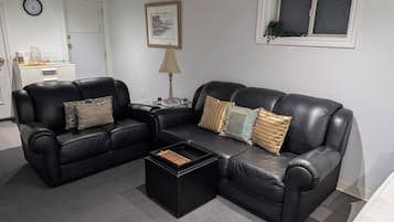 A living room with a black leather sofa, a coffee table, and a side table with a lamp.