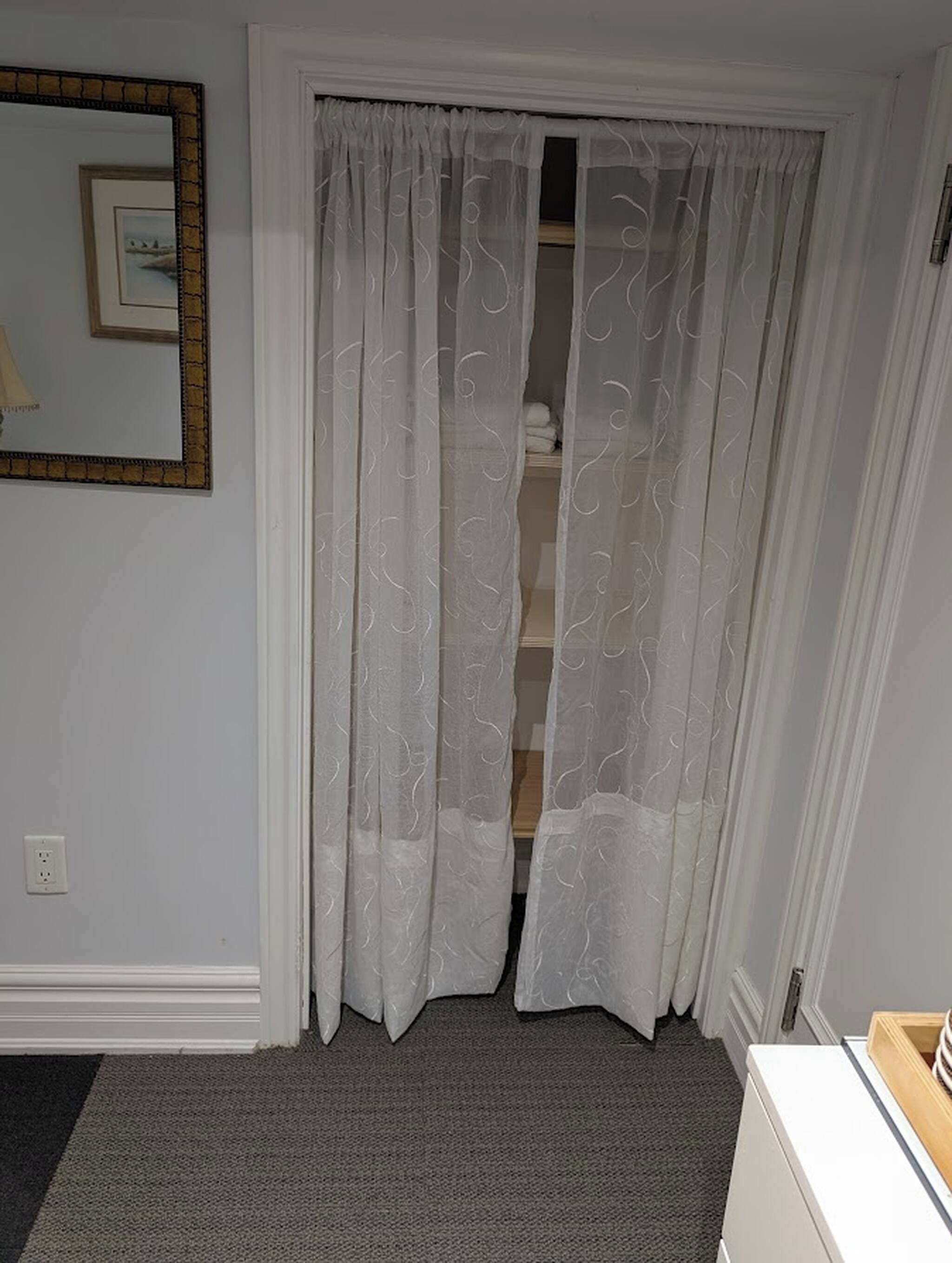 Una habitación con una puerta blanca, un espejo y piso alfombrado.