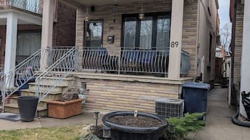 Un edificio residencial de dos pisos con un balcón, una puerta principal y un número de casa visible.