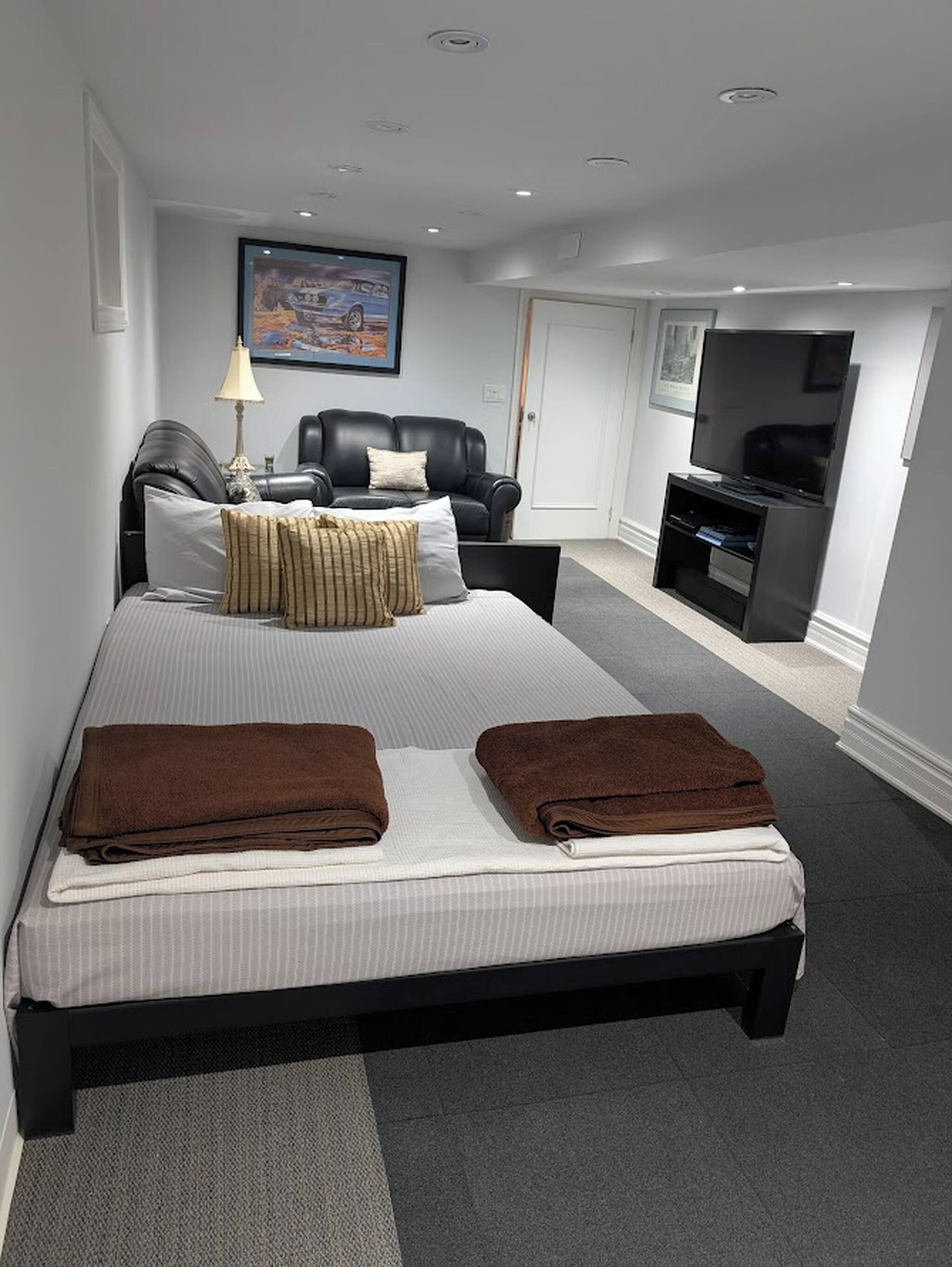Una habitación de hotel moderna con una cama grande, un televisor de pantalla plana, un sofá y un cuadro en la pared.