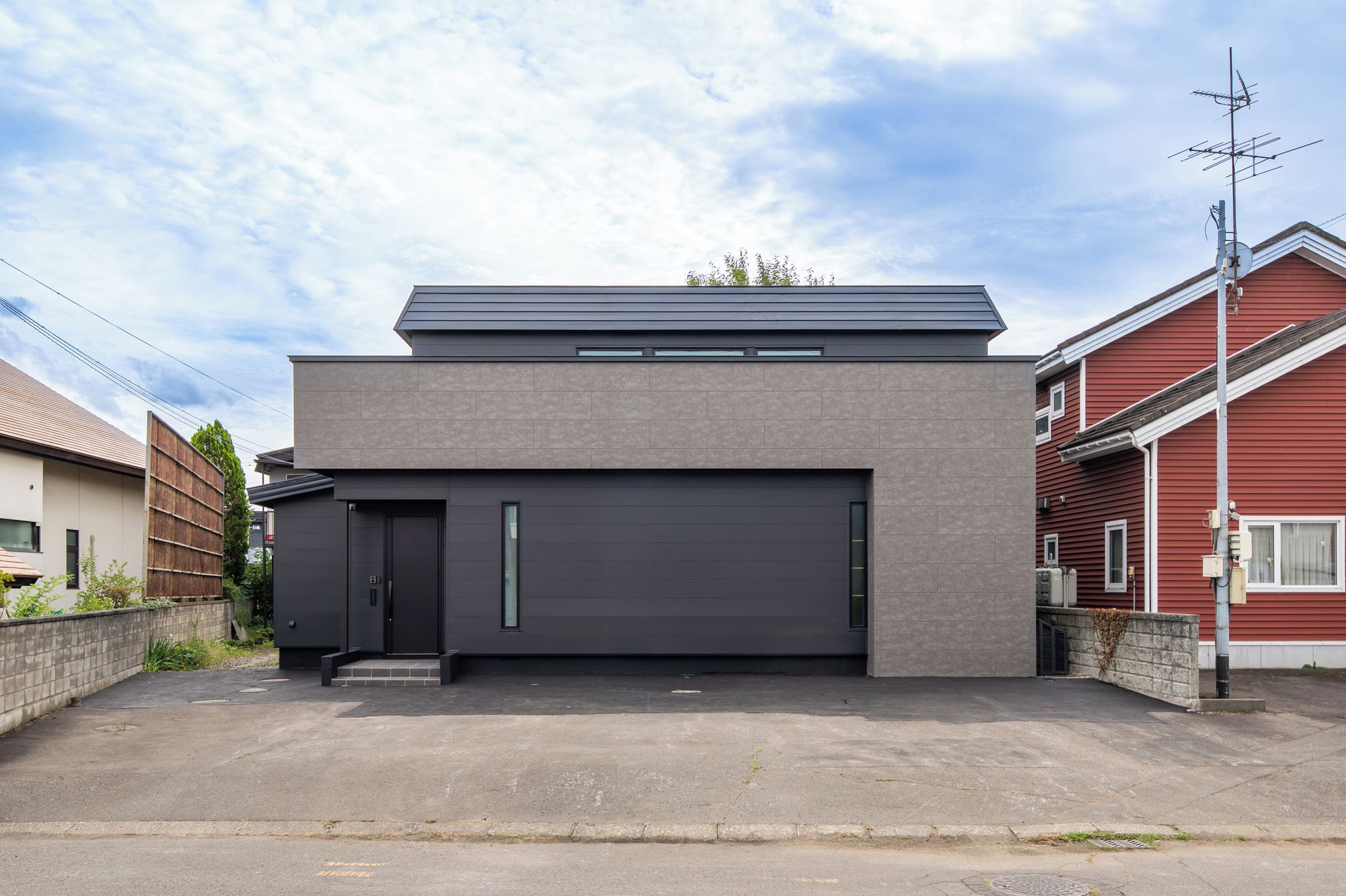 A modern two-story house with a dark grey garage door, a flat roof, and a small overhang.