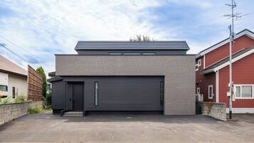 A modern two-story house with a dark grey garage door, a flat roof, and a small overhang.