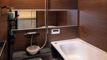 A modern bathroom with a bathtub, shower, and toilet.