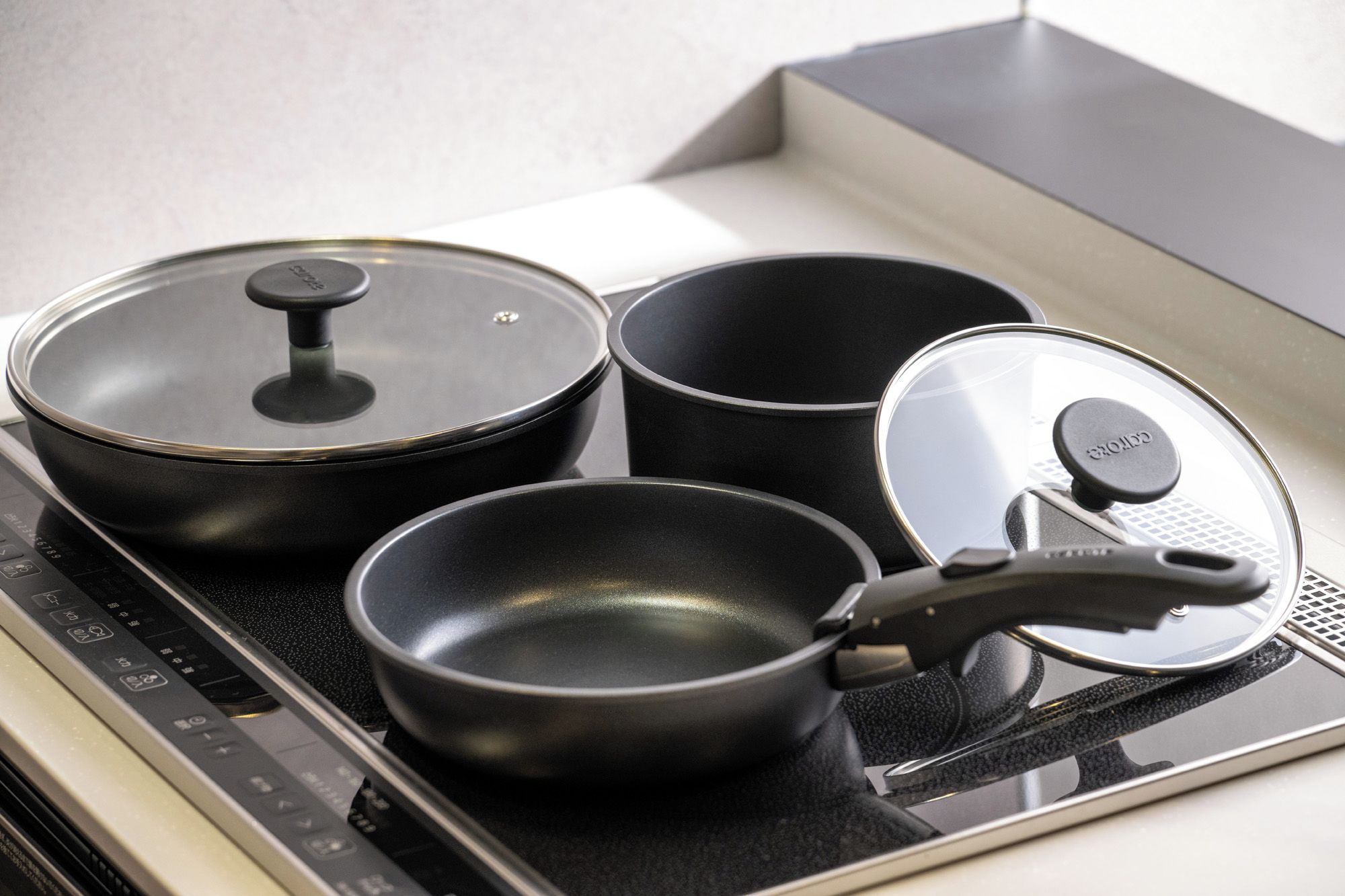 A kitchen with a stove, three pots, and a pan.
