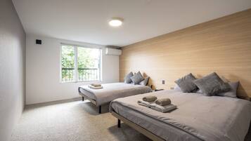 A modern bedroom with two beds, a large window, and a ceiling light.
