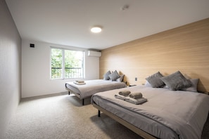 Un dormitorio moderno con dos camas, un ventanal grande y una lámpara en el techo.