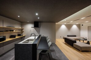 Cocina moderna con una isla central, electrodomésticos integrados y un comedor con sofá y mesa.