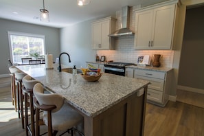 A modern kitchen with a granite island, bar stools, and a built-in oven.
